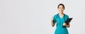Healthcare workers, preventing virus, quarantine campaign concept. Smiling pretty asian doctor, female intern in scrubs Royalty Free Stock Photo