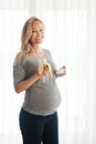 Only the healthiest food for my little one. Portrait of a happy pregnant woman eating a banana and drinking a glass of