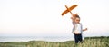 Healthy active child girl plays alone with a toy airplane on a summer field launches into the sky and dreams of becoming
