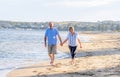 Healthy active senior couple holding hands, embracing each other and walking on beach Royalty Free Stock Photo