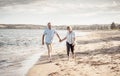 Healthy active senior couple holding hands, embracing each other and walking on beach Royalty Free Stock Photo