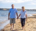 Healthy active senior couple holding hands, embracing each other and walking on beach Royalty Free Stock Photo