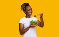 Healthy african woman eating fresh salad over yellow Royalty Free Stock Photo