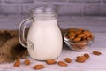 Healthy almond milk in a jug and almonds on a white wooden background. Royalty Free Stock Photo