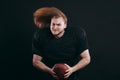 Confident american football player in black sportwear holding helmet and ball Royalty Free Stock Photo