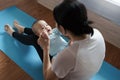 Healthy Asian mother in sportswear playing and holding her baby boy son hands while practicing yoga and exercise at home Royalty Free Stock Photo