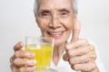 Healthy asian senior grandmother drinking a glass of vitamin C,orange juice,smiling elderly people with effervescent vitamin C,