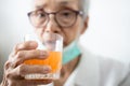 Healthy asian senior woman is drinking a glass of vitamin C or orange juice,elderly people with effervescent vitamin C,