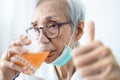 Healthy asian senior woman is drinking a glass of vitamin C or orange juice,elderly people with effervescent vitamin C,