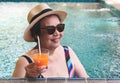 Healthy Asian senior  woman wearing straw hat and sunglasses  drinking  orange juice  in the swimming pool, smiling and looking Royalty Free Stock Photo