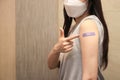 Healthy asian woman concept of recommended inoculation, Woman holding down her shirt sleeve and showing her arm with bandage afte