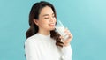 Healthy Asian woman drinking a glass of milk on blue background Royalty Free Stock Photo