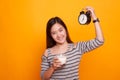 Healthy Asian woman drinking glass of milk hold clock. Royalty Free Stock Photo