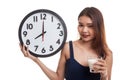 Healthy Asian woman drinking glass of milk hold clock. Royalty Free Stock Photo