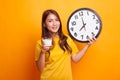 Healthy Asian woman drinking glass of milk hold clock in yellow Royalty Free Stock Photo