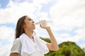 A healthy Asian woman is drinking water from a bottle, feeling thirsty, resting after a long run Royalty Free Stock Photo