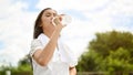 A healthy Asian woman is drinking water from a bottle, resting after a long run on a hot, sunny day Royalty Free Stock Photo