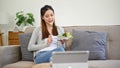 Healthy Asian woman eating her fresh and organic salad while relaxing in her living room Royalty Free Stock Photo