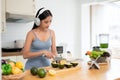 A healthy Asian woman is listening to music while preparing her breakfast in the kitchen Royalty Free Stock Photo