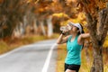 Healthy athletic asian woman is drinking pure water from the bottle refreshing herself after exercise in the autumn nature park. Royalty Free Stock Photo