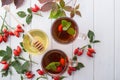 Healthy autumn drink with hip roses ,branch with berries on white background.