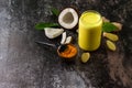 Healthy ayurvedic drink golden coconut milk with curcuma powder ginger on a stone countertop.