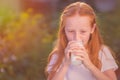 Healthy baby milk. Portrait of a beautiful redhead girl drinking fresh milk outdoors. Milk is fresh from the cow Royalty Free Stock Photo