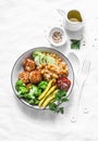 Healthy balanced buddha bowl lunch - spicy couscous with chickpeas, broccoli, green beans and turkey meatballs on light background