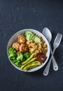 Healthy balanced buddha bowl - spicy couscous with chickpeas, broccoli, green beans and turkey meatballs on dark background, top v