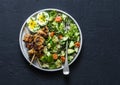 Healthy balanced lunch bowl - turkey skewers, quinoa, avocado, cucumber salad and boiled egg on dark background, top view.