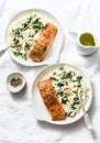 Healthy balanced lunch - creamy spinach orzotto and baked salmon on a light background, top view