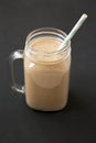 Healthy banana apple smoothie in a glass jar over black background, low angle view. Close-up Royalty Free Stock Photo