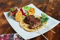 Healthy barbecued lean cubed pork kebabs served with a corn tortilla and fresh lettuce and tomato salad, close up view