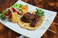 Healthy barbecued lean cubed pork kebabs served with a corn tortilla and fresh lettuce and tomato salad, close up view Royalty Free Stock Photo