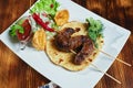 Healthy barbecued lean cubed pork kebabs served with a corn tortilla and fresh lettuce and tomato salad, close up view Royalty Free Stock Photo