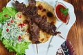 Healthy barbecued lean cubed pork kebabs served with a corn tortilla and fresh lettuce and tomato salad, close up view