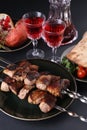 Healthy barbecued lean cubed pork kebabs served with tomato,pita, greens, garnet and two glasses of red drink, close up