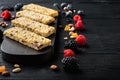 Healthy bars with nuts, seeds and berries with space for text, on black wooden table Royalty Free Stock Photo