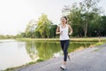 Healthy beautiful young Asian runner woman in sports clothing running and jogging on sidewalk near lake at park in the morning. Royalty Free Stock Photo