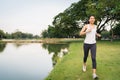 Healthy beautiful young Asian runner woman in sports clothing running and jogging on sidewalk near lake at park in the morning. Royalty Free Stock Photo