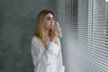 healthy beautiful young woman stands at home near the window drinking clean water from a glass. Royalty Free Stock Photo