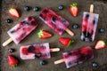Healthy berry fruit popsicles, flat lay on a dark background