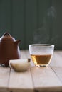 Healthy beverage concept. Steaming hot Chinese old shen puerh tea in glass chahai and onyx stone cup on white wooden table copy Royalty Free Stock Photo