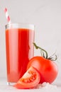 Healthy beverage - fresh vegetable tomato juice, straw, salt and red tomatoes on soft white wood background, macro, vertical. Royalty Free Stock Photo