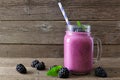 Blackberry smoothie in a mason jar with scattered berries over wood Royalty Free Stock Photo