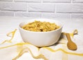 Healthy Bowl of Corn Flakes and Wooden Spoon on Yellow Napkin on White backround