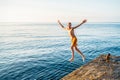 Healthy boy jumps into tranquil ocean water from stone pier