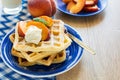 Healthy breakfast: Belgian waffles with peach slices and cream decorated mint leaves and blue napkin