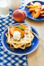 Healthy breakfast: Belgian waffles with peach slices and cream decorated mint leaves and blue napkin