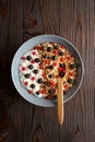 Bowl with oat granola, yogurt and black raspberries, black and red currants on a brown wooden background. Royalty Free Stock Photo